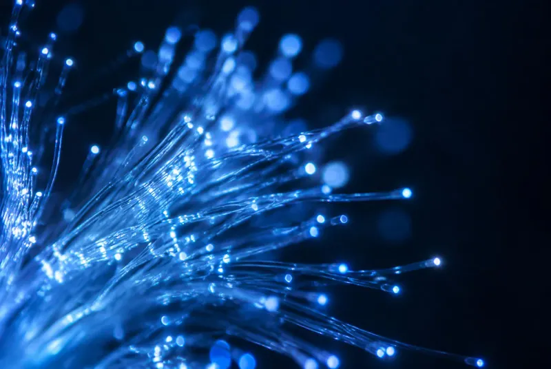 Glowing blue optical fibres in a macro shot against a dark background